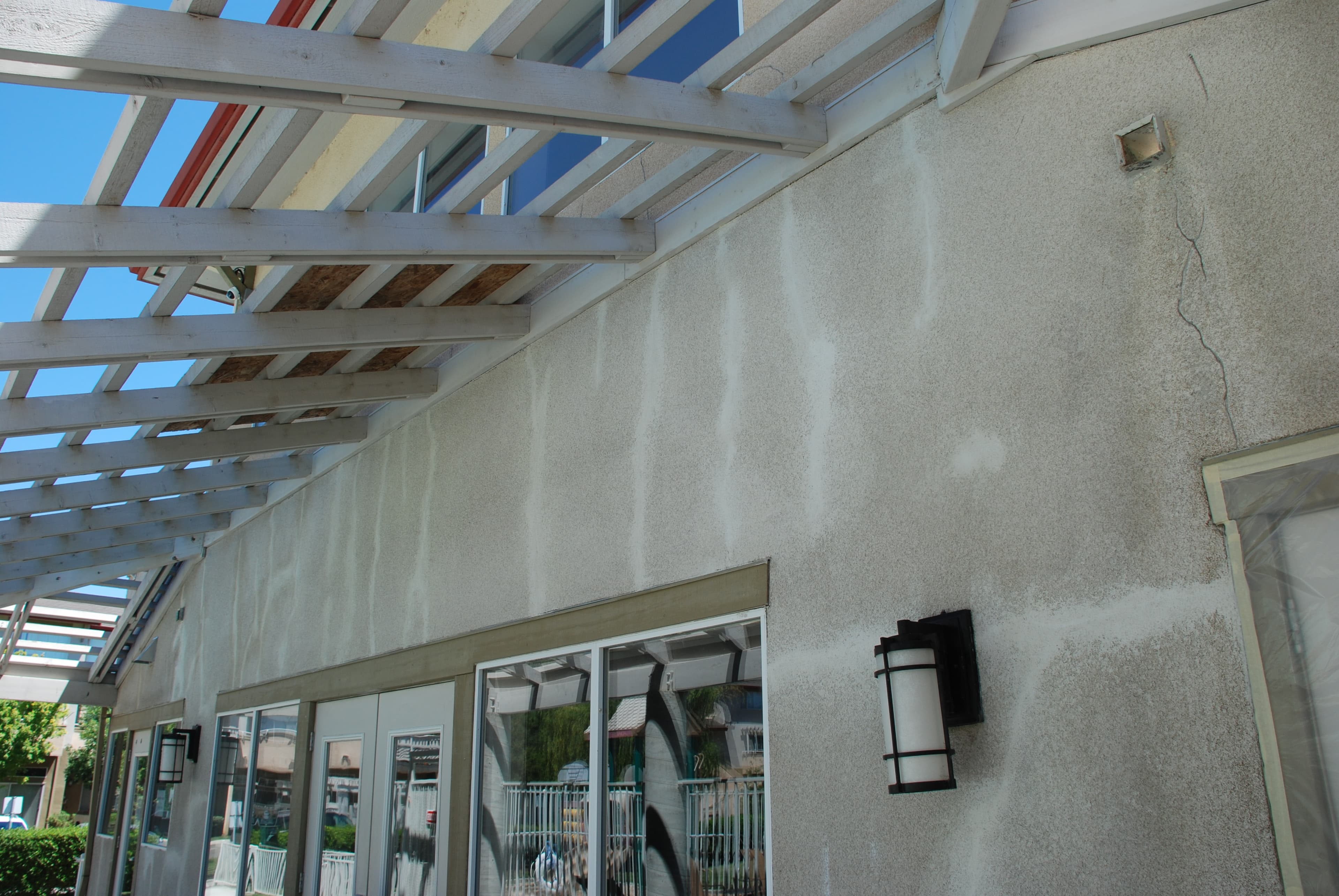 A stucco wall with cracks and marked repair areas during an exterior repair project