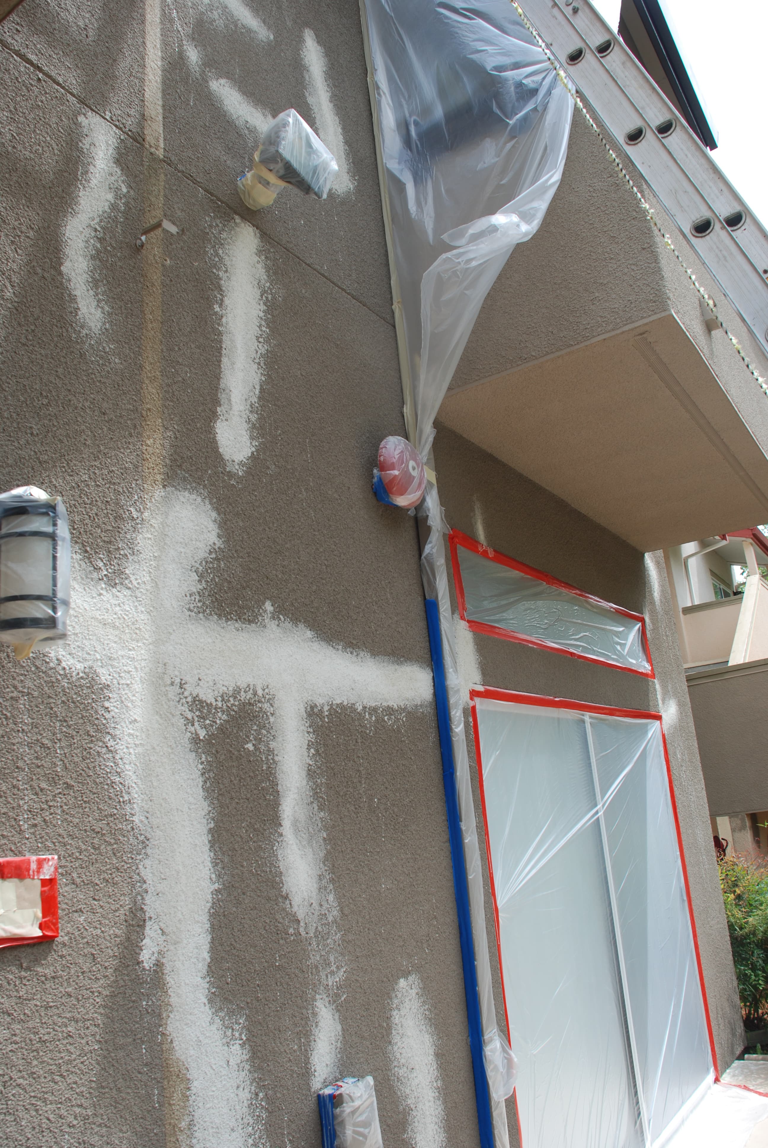 Cracks extending through stucco near a window and along the exterior wall