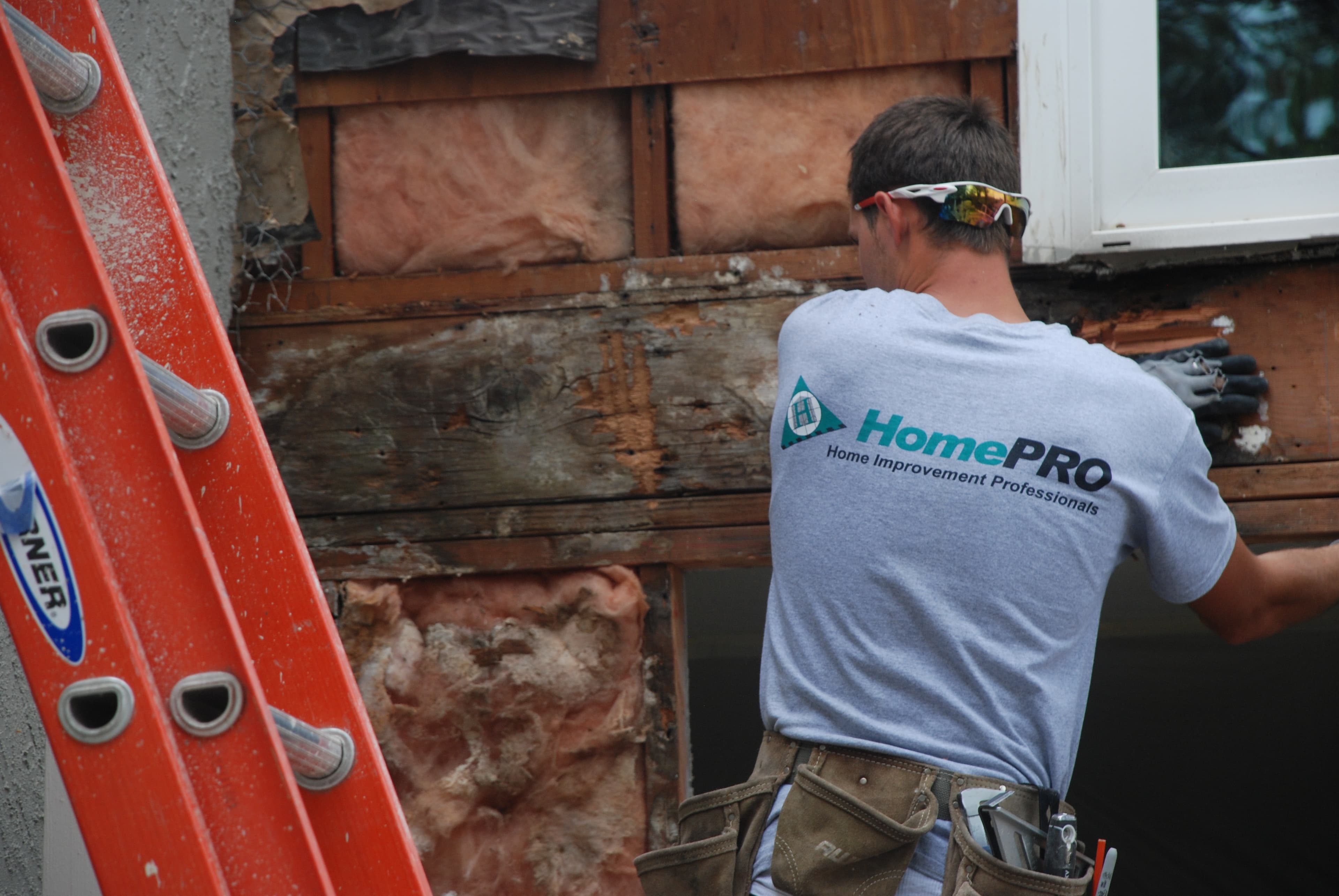 HomePRO specialist inspecting exposed wall framing and water damage during stucco leak detection